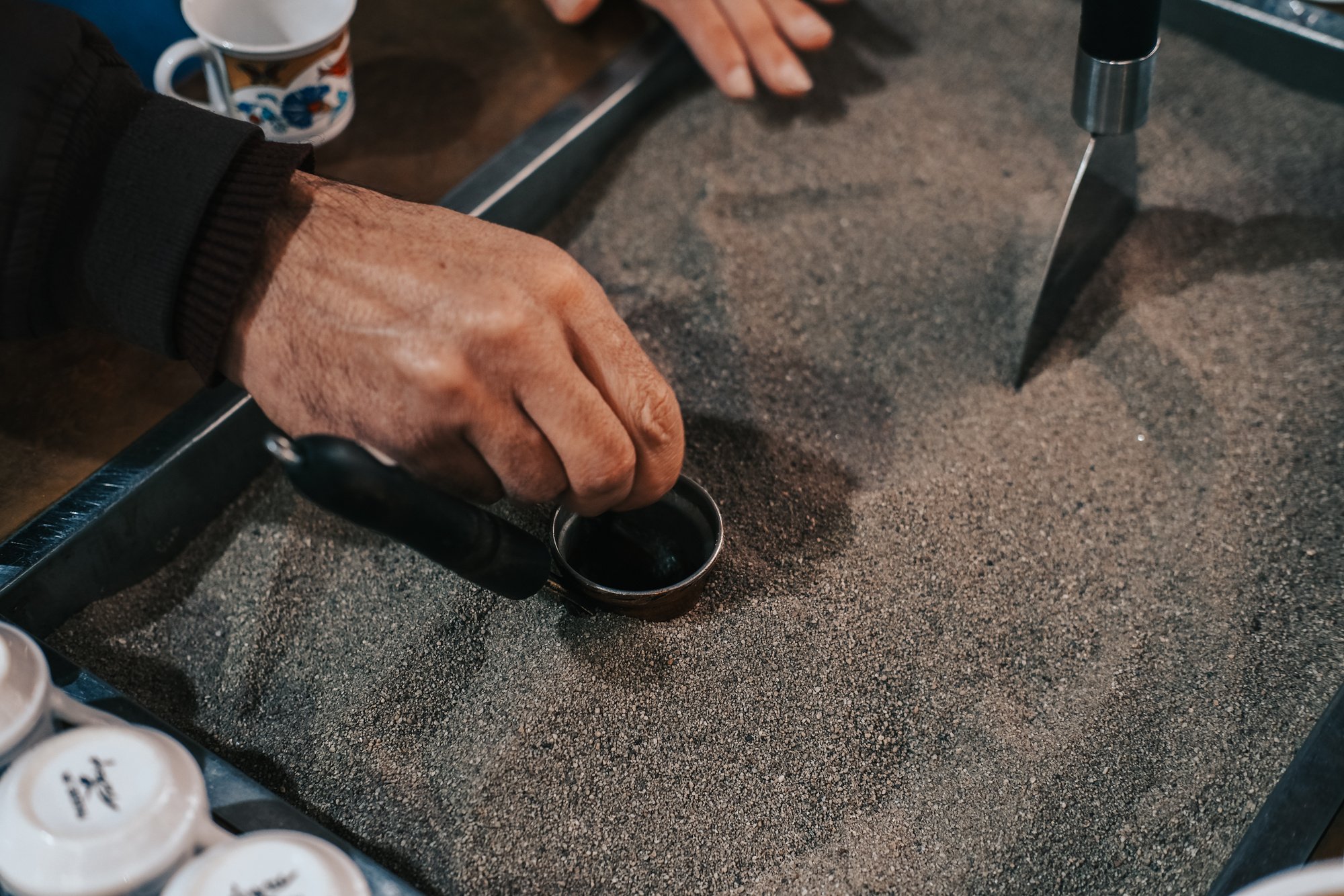 Man Making Traditional Turkish Coffee in Sand